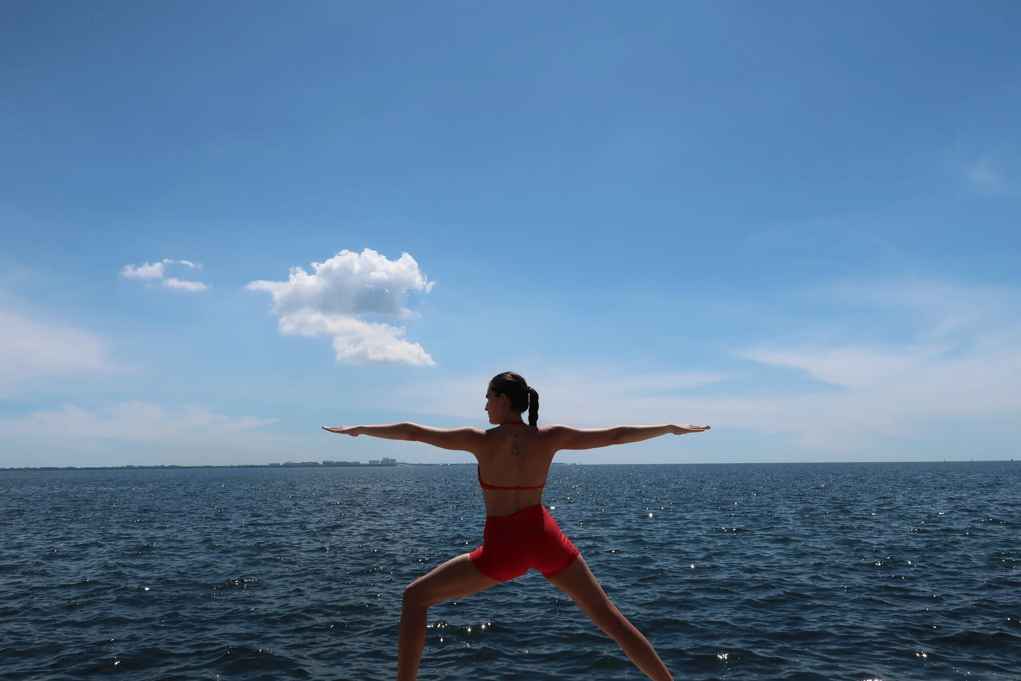 Tatiana Gentile in Warrior II facing the ocean